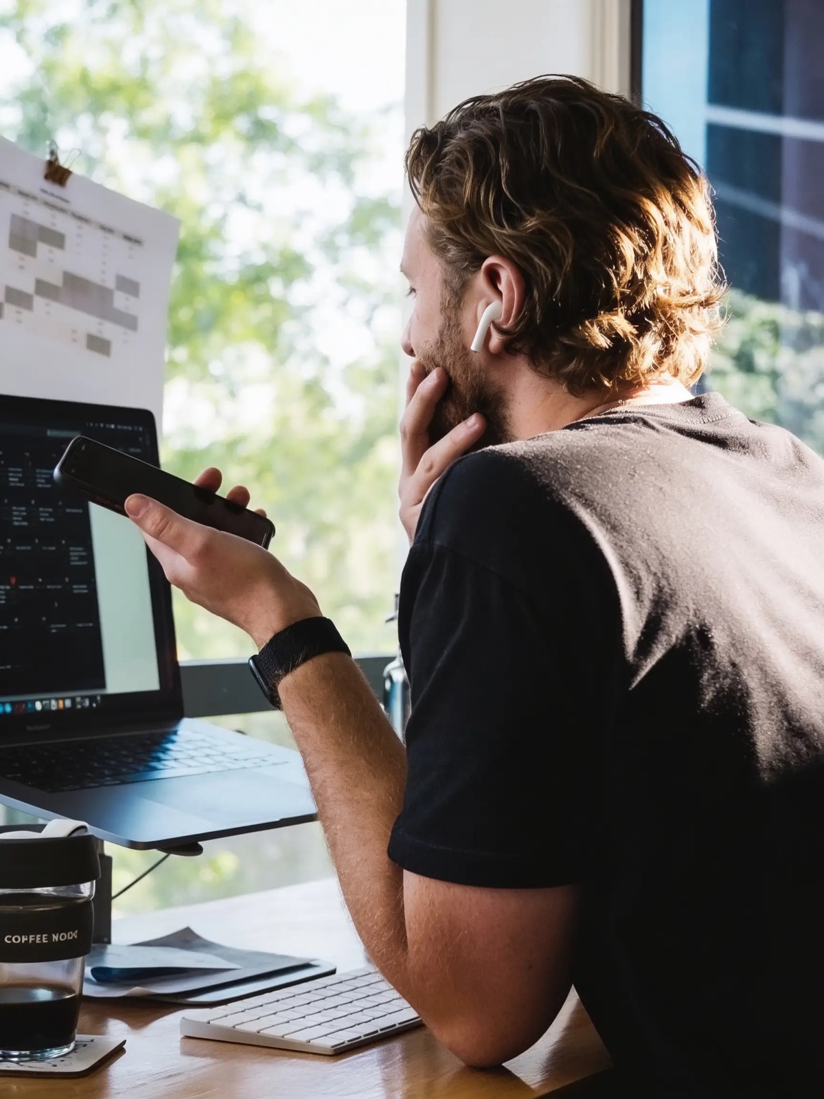 Person vid skrivbord med laptop och telefon